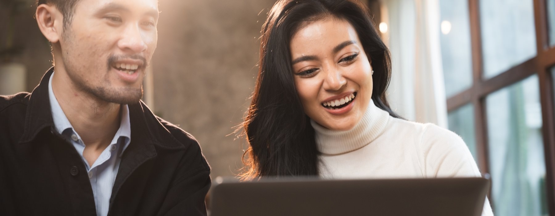 a man and woman looking at a computer together